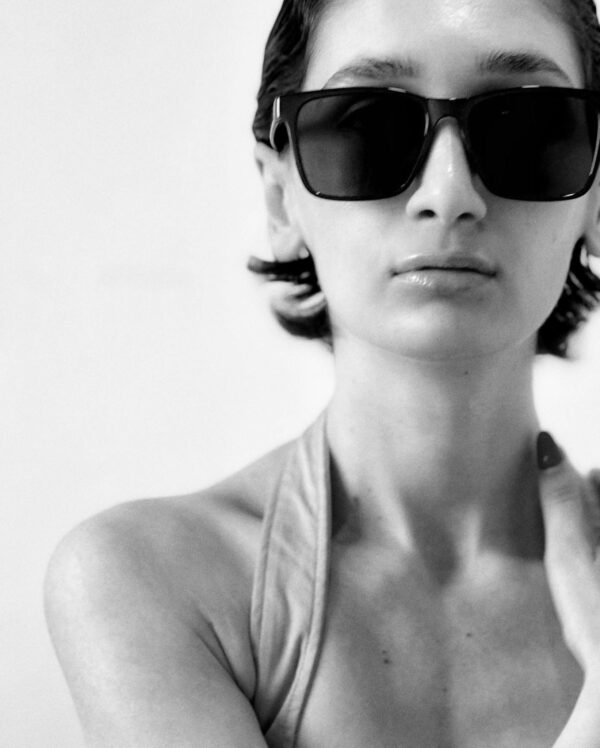 Monochrome portrait of a woman wearing fashionable sunglasses and a stylish top.